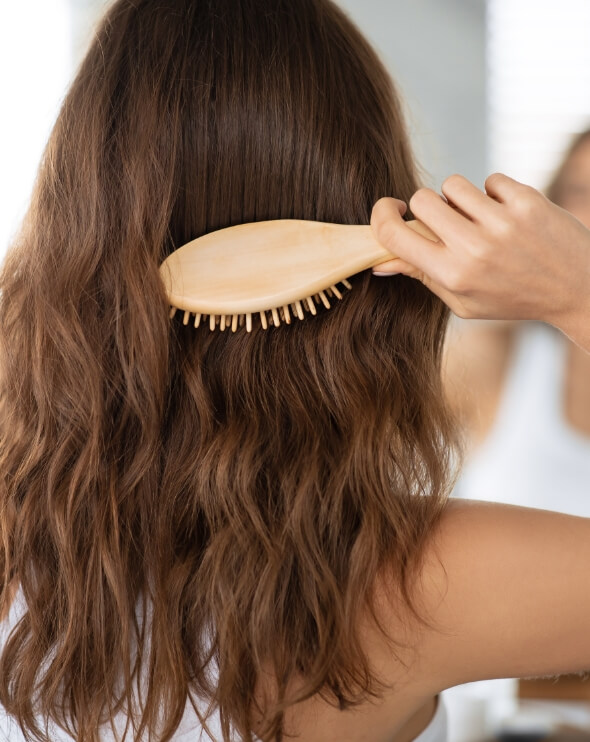 lady-brushing-hair-with-wooden-hairbrush-in-bathro-2023-11-27-05-25-11-utc